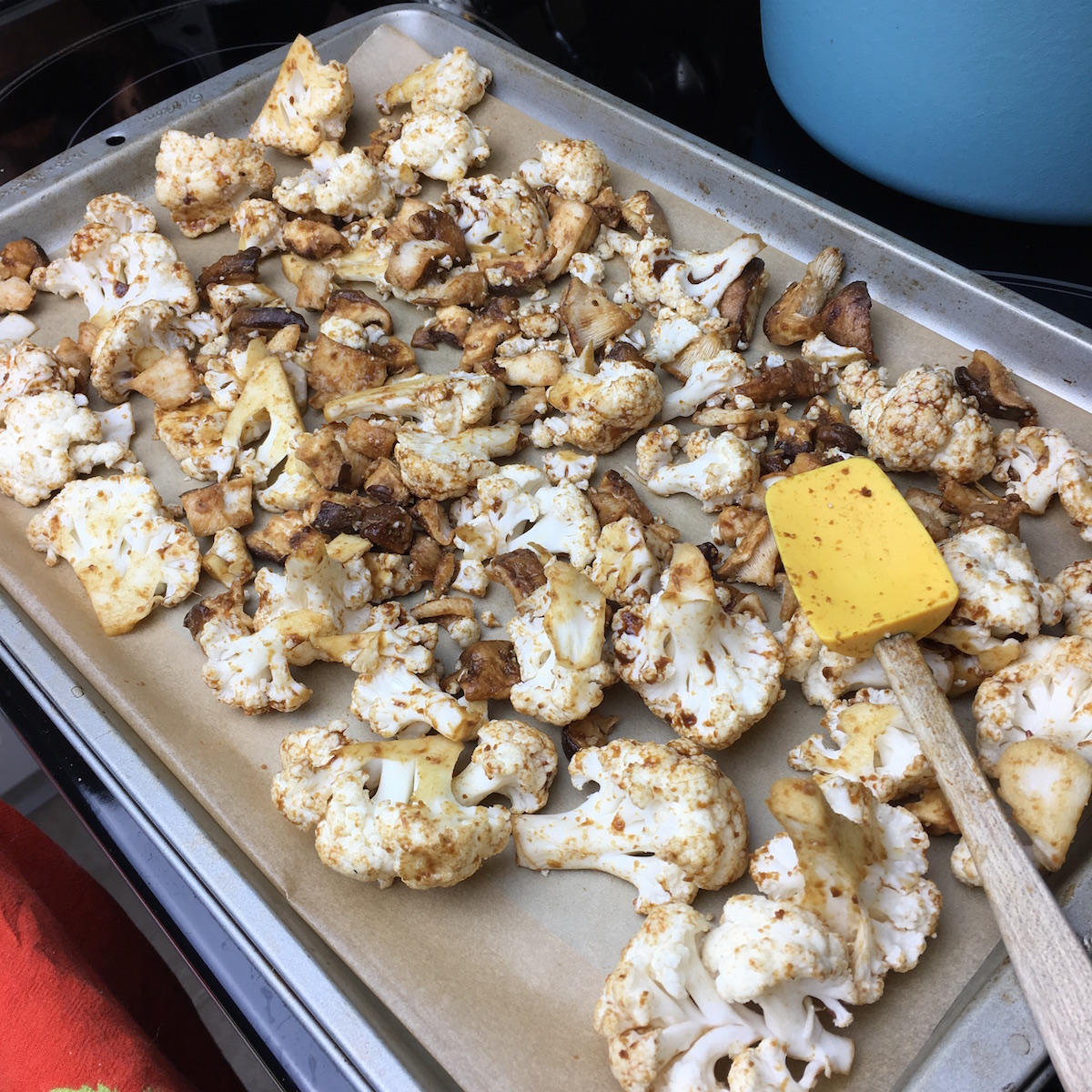 Cauliflower and mushrooms spread out on parchment paper. 